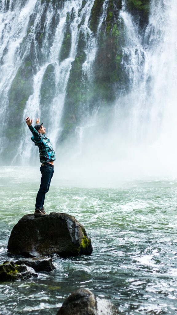 Photo by Slav Romanov man standing on black rock surrounded body of water